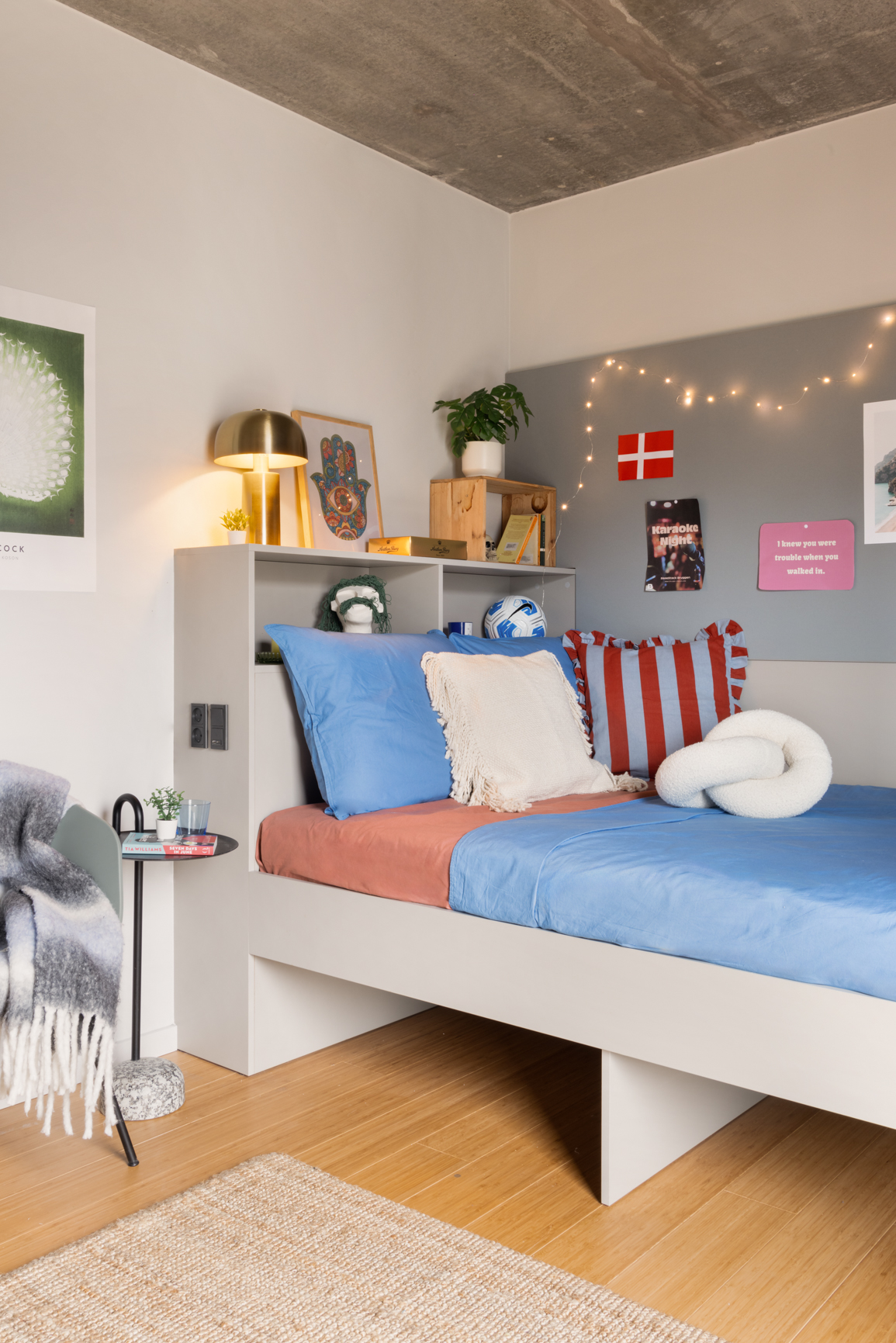 The Giant Studio with 140cm bed, shelving above the bed and corner chair in Basestack Living student accommodation and apartments to rent in Copenhagen
