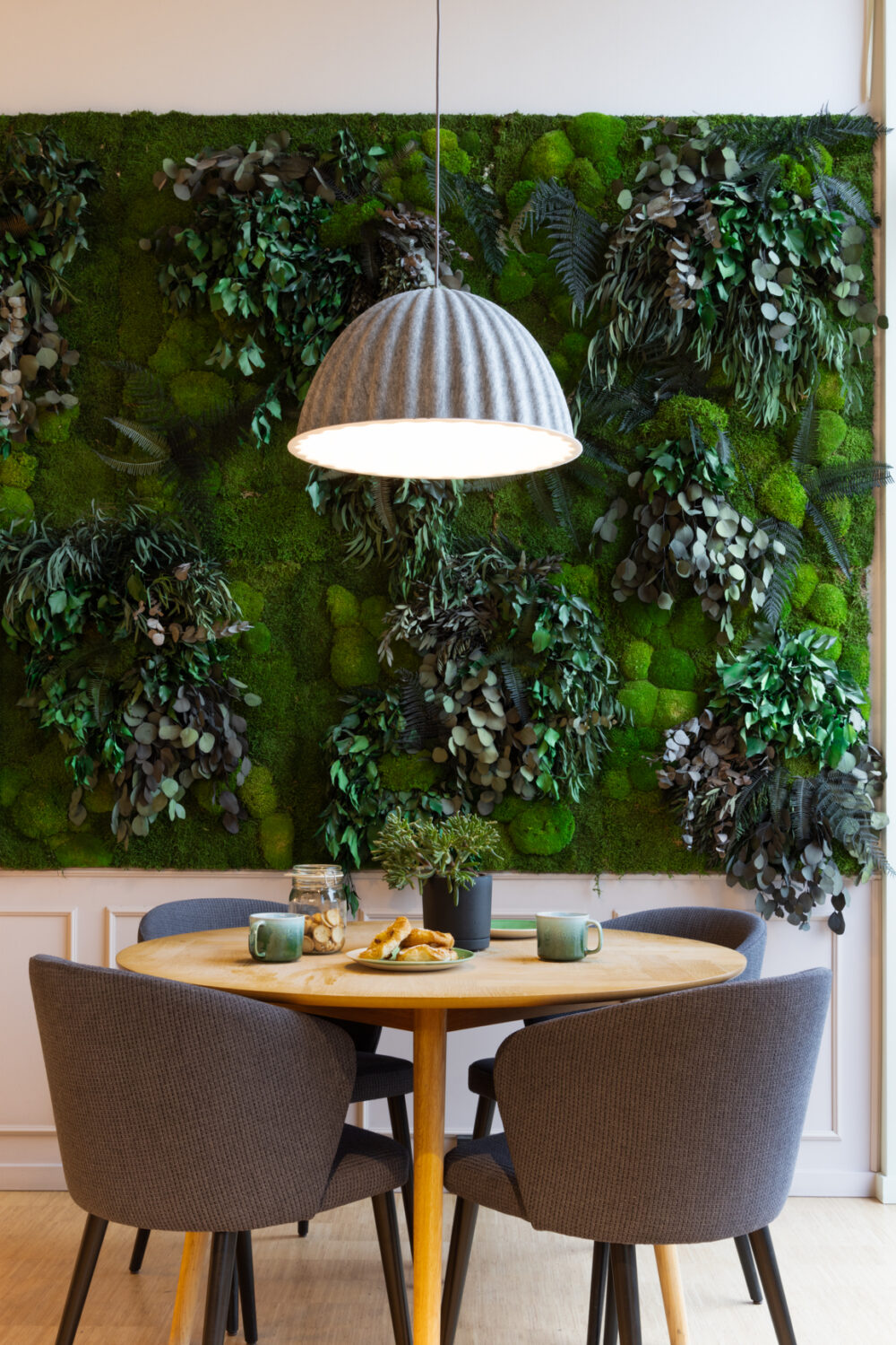 Table with 4 chairs in coffee area, in front of live green plant wall in BaseStack student accommodation and apartments to rent in Copenhagen